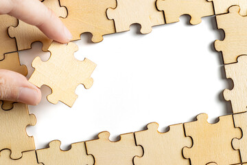 hand holding wooden jigsaw puzzle pieces. To complete the puzzle. business and teamwork concept.