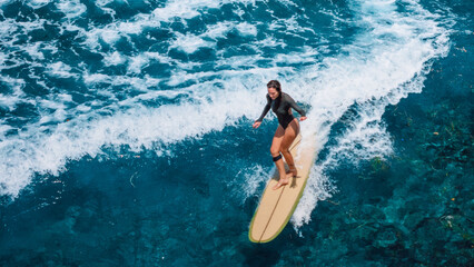Woman surfer ride on longboard on ocean wave. Drone view of woman during surfing