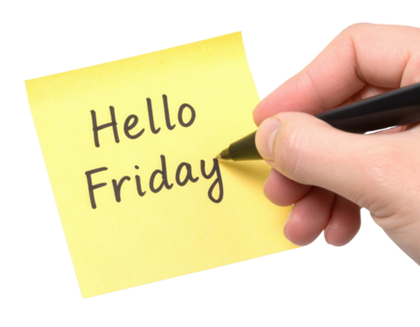 A hand is writing "Hello Friday" in black ink on a yellow sticky note with a black pen.