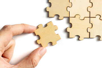 hand holding wooden jigsaw puzzle pieces. To complete the puzzle. business and teamwork concept.
