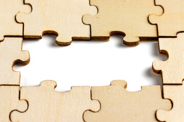 wooden jigsaw puzzle with missing pieces exposing empty white background for copy space.
