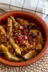 homemade recipe of artichokes with ham au gratin in a brown earthenware casserole dish