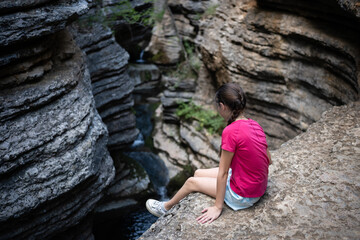 Young hiker contemplating waterfall in scenic canyon