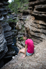 Young girl contemplating nature's beauty while sitting on a cliff overlooking a canyon
