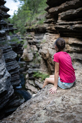 Young hiker contemplating amazing canyon from cliff edge