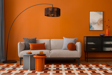 Modern living room with orange wall, curved floor lamp and cozy grey sofa with colorful pillows....