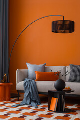 Modern retro living room featuring a black arc lamp, orange side table and warm-toned cushions.