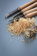 Chisels and wood shavings in craftsman's workshop on gray background
