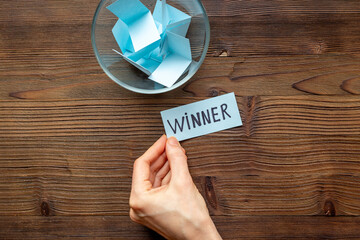 Hand is picking a winner ticket from glass jar, top view. Luck and lottery concept.
