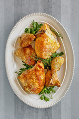 roasted beer can chicken pieces on a platter served with peas and corn