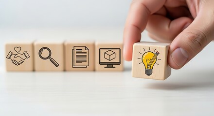 In a warm, natural light setting, a person arranges wooden cubes featuring icons of partnership, search, documentation, and a brilliant idea, illustrating the strategic development and future design o