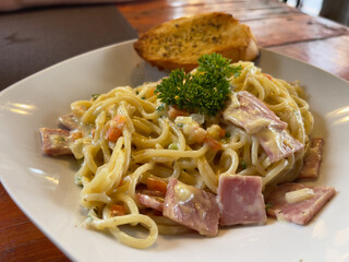 Spaghetti carbonara with ham and parmesan on wooden table