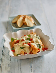 baked chicken caprese with tomatoes, melted mozzarella, and fresh basil, served with toasted baguette slices