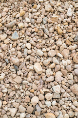 Textured surface of small gravel stones in various shades of gray and beige, creating a natural vertical background for landscaping, construction, or decorative purposes. Copy space