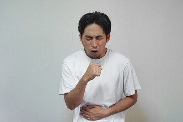 Man in white t-shirt experiencing stomach pain and coughing.