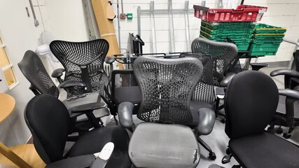 Multiple used office chairs in a basement storage area, signaling clutter and reuse.