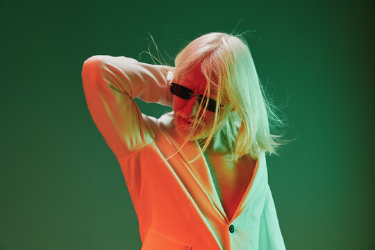 Stylish person with long hair and sunglasses in a creative studio setting, vibrant colors creating a modern atmosphere with dynamic light effects enhancing the visual appeal