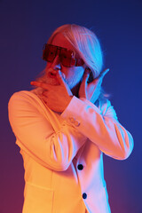 Stylish elderly man posing in colorful lighting, emphasizing fashion and individuality Background...