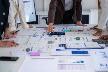 A group of people are looking at a table full of papers and graphs