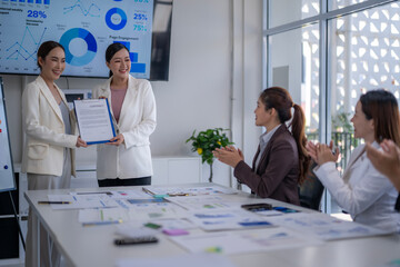 A woman is holding a certificate in front of a group of women
