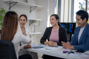 A group of people are sitting around a table with a woman in a white shirt