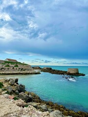 Dramatic view of the Atlantic Ocean from a causeway, under stormy skies. A white coastal town sits...