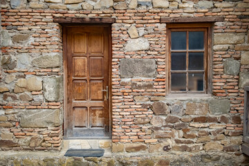 Rustic stone wall with wooden door and window in an old building in a historic village