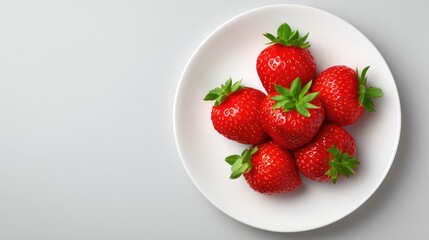Bright red strawberries clustered in the corner of a white plate with empty space around, top view