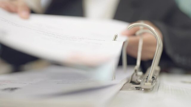 A person is holding a ring binder with a piece of paper in it. The paper is open to a page with writing on it