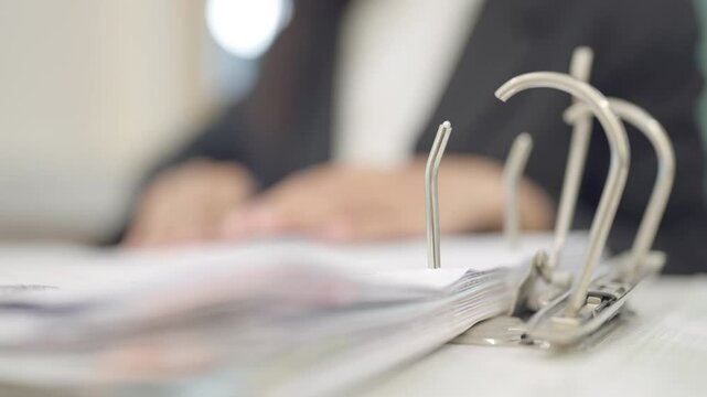 A person is holding a binder with a paper inside. The paper is open to a page with a word on it