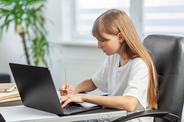 Teen girl learning online and taking notes. Back to school.
