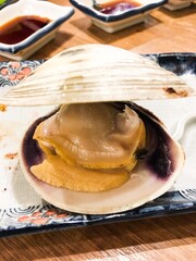 vertical photo of close up of a grilled short necked clam or Guifei Clam on the dining table