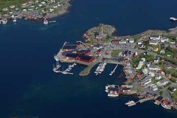 view of a coastal fishing village in Norway with red houses, piers, and clear blue fjord waters.