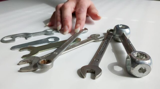 Woman choosing tool from multiple spanner tools on worktop, close up