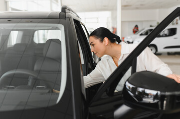 Young woman choosing a car at car showroom