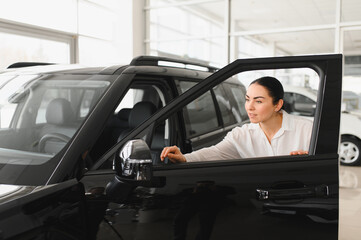 Lady in a car salon. Woman buying the car. In a white shirt