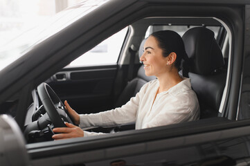 Young woman choosing a car at car showroom