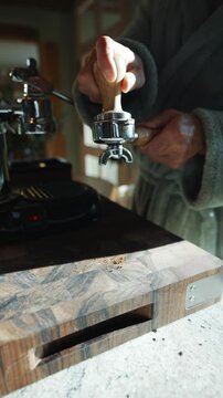 A person is grinding coffee beans with a grinder. The coffee beans are in a small container and the grinder is being used to grind them