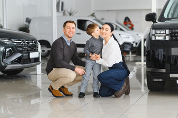 Family in a car dealership. Happy family choosing a new car in a showroom