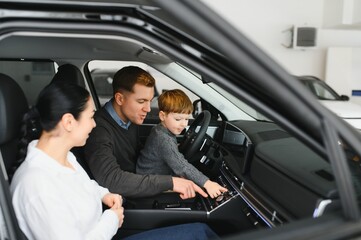 Family in a car dealership. Happy family choosing a new car in a showroom