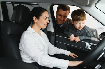 Beautiful young family choosing a new car in a car showroom