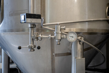 Pressure valve and gauge on stainless steel fermentation tank in modern craft brewery