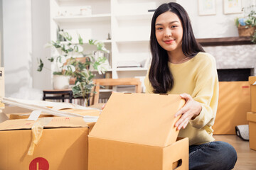 Asian smiling woman with cardboard boxes for moving to the new home. Concept of people moving...