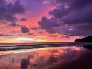 tropical sunset on the beach with dramatic clouds and reflections