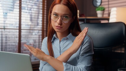 Caucasian businesswoman working laptop in office looking at camera crossed hands in stop enough...