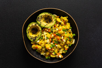 A hearty salad combines boiled egg, chicken breast, vibrant carrots, tender potatoes, green peas, and creamy avocado sprinkled with sesame seeds, all enhanced with olive oil