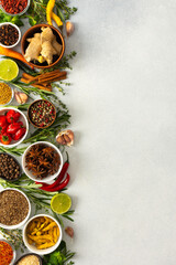 Various cooking spices and herbs spread across a neutral gray background, showcasing their rich,...