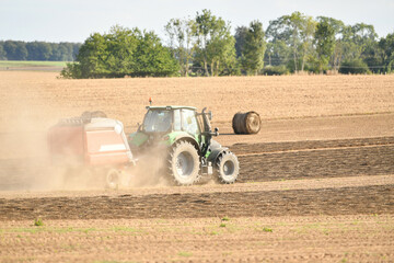 A tractor cleans the field with flax and makes bales