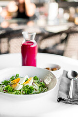 Healthy salad with boiled eggs, parsley, cucumber, and nuts served with beet juice on a white table. Clean, fresh, and nutritious meal concept, top view.