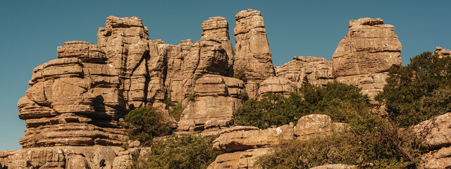 Limestone rock formations like pillars between green vegetation under a blue sky. National park El...